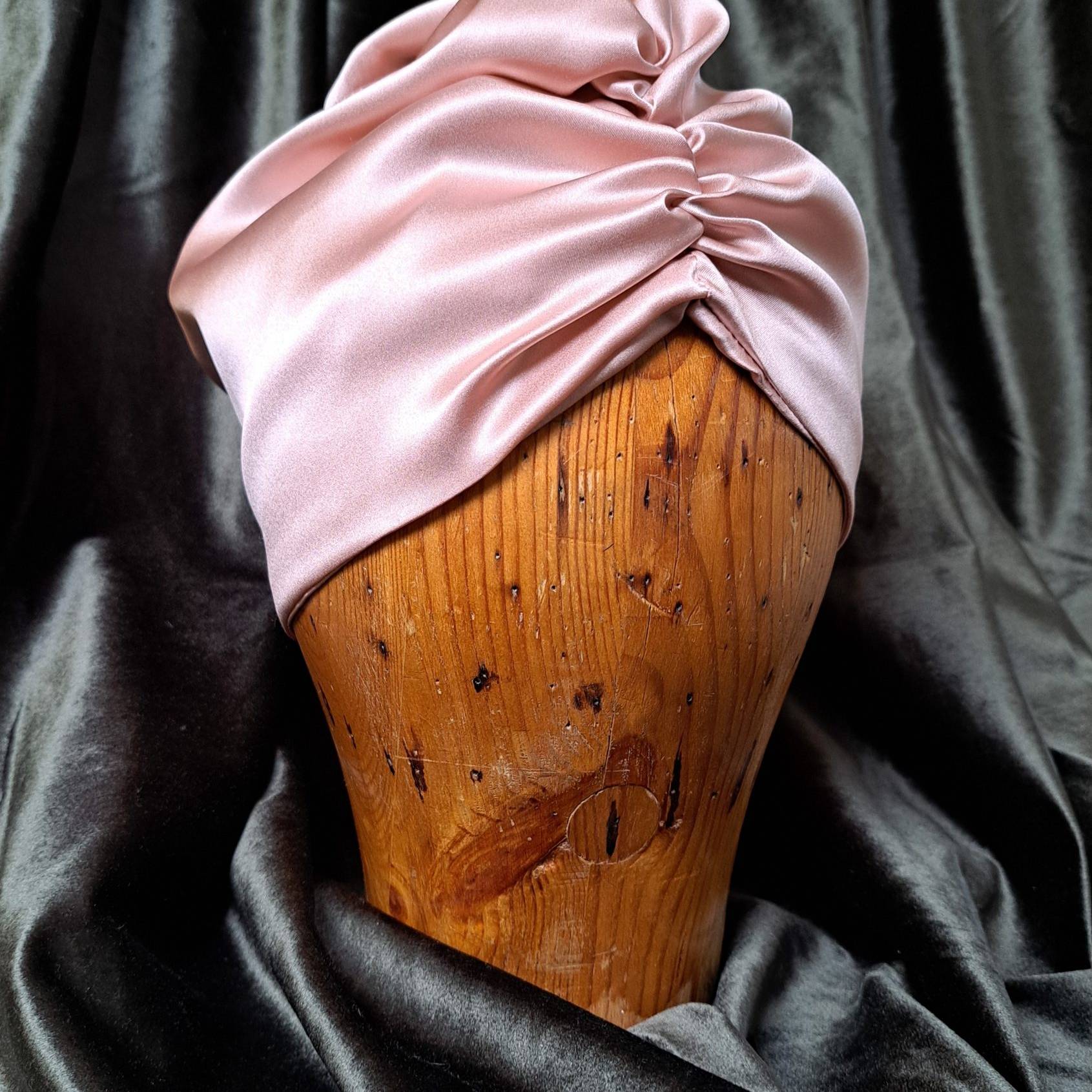 Unibonnet headgear in a wooden rack. Surrounded by dark velvet.