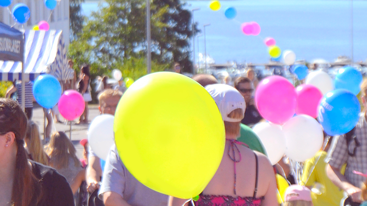 Ihmisjoukkoa sekä värikkäitä ilmapalloja.