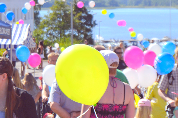 A crowd of people and colourful balloons.